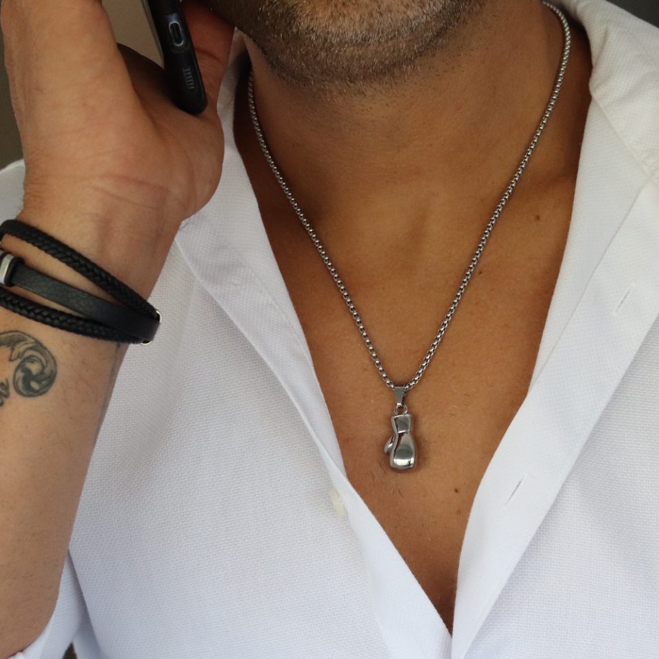 שרשרת כפפת איגרוף בכסף על גבר עם חולצה מכופתרת לבנה