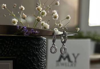עגילי חישוק עם אות משובצת ליד אריזת My Jewelry